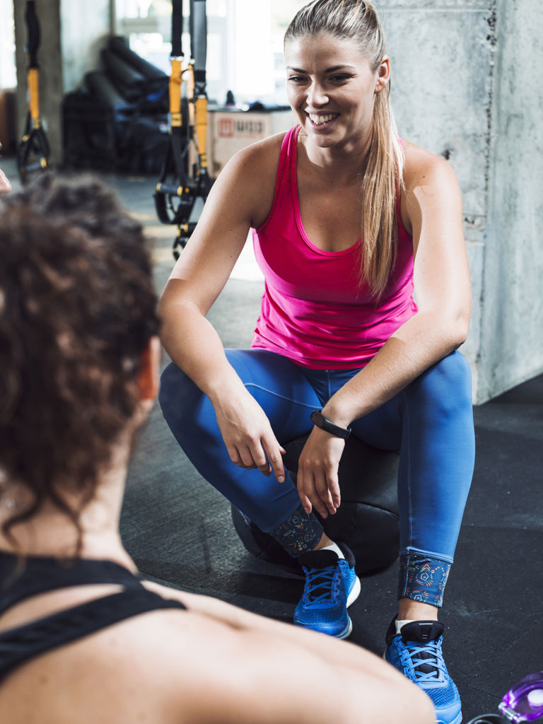 Happy Young Woman Sitting Near Her Friend Gym