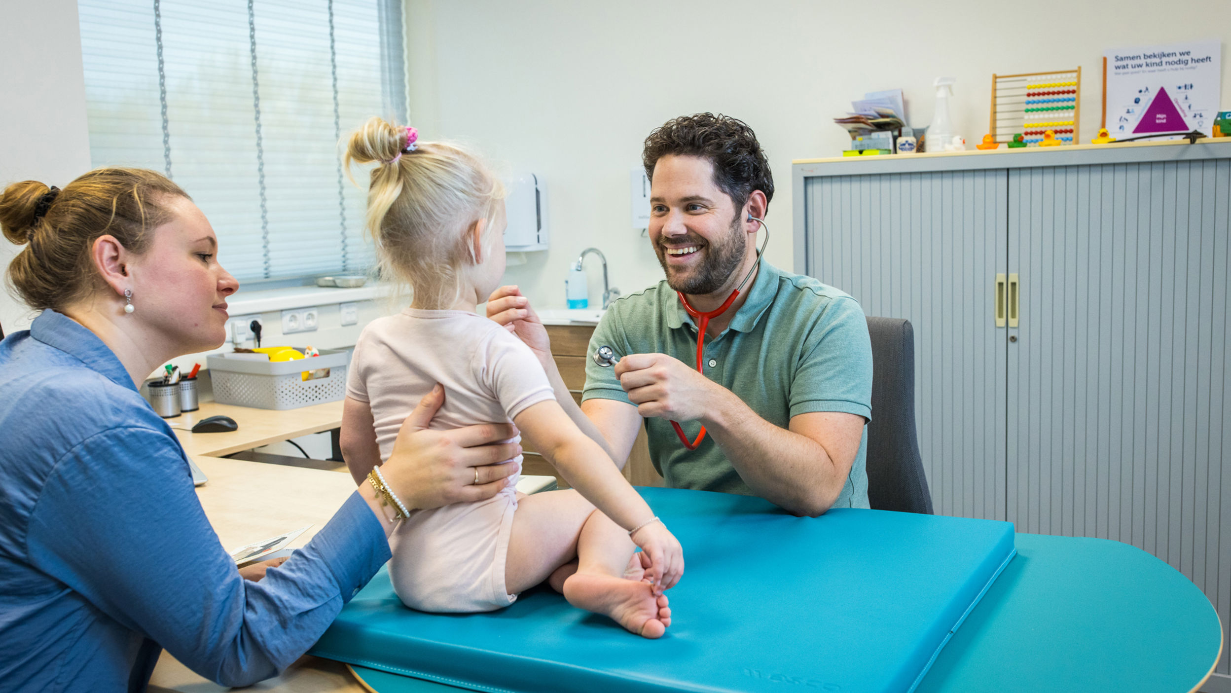 Jeugdarts Onderzoekt Lachend Kind En Moeder Houdt Haar Vast
